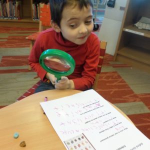 photo of boy looking through magnifying glass